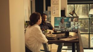 Two people at a desk, collaborating while looking at a computer screen together