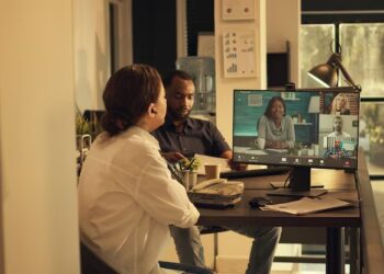 Two people at a desk, collaborating while looking at a computer screen together
