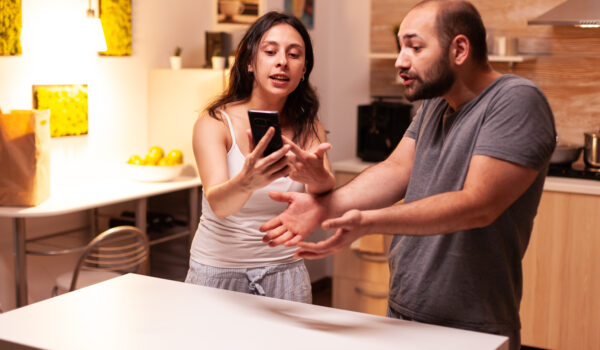 Woman pointing at phone while reading messages of infidel husband while having a disagreement.