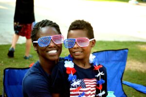 Black American mother and son wearing matching USA flag inspired sunglasses, locate birth parents in the United States concept