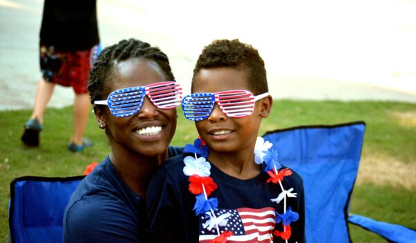 Black American mother and son wearing matching USA flag inspired sunglasses, locate birth parents in the United States concept