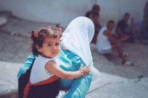 Moroccan girl piggy back riding on her mother's back; locate birth parents in Morocco concept