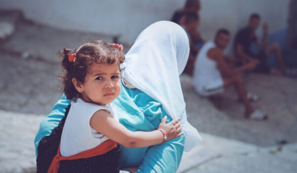 Moroccan girl piggy back riding on her mother's back; locate birth parents in Morocco concept