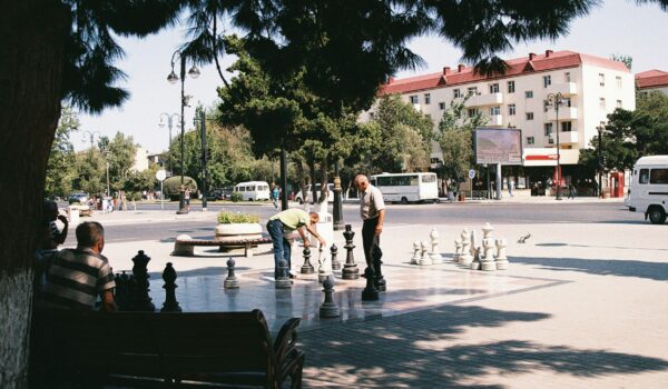 group of old Azerbaijanis playing giant chess in a park; locate birth parents in Azerbaijan concept