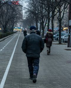 old Bulgarian man walking on a side walk with people walking before him; locate birth parents in Bulgaria concept