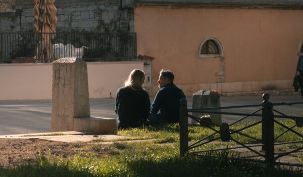 couple sitting by a field of grass; locate birth parents in Croatia concept