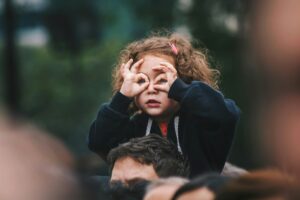 Argentinian girl sitting over her father's shoulders making goggles with her hands; locate birth parents in Argentina