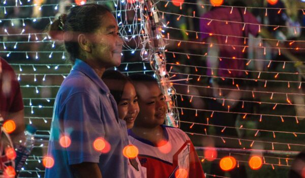 Thai mother posing with her two kids with lights around; locate birth parents in Thailand concept