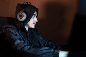 A man in a hoodie wearing headphones, focused and immersed in listening to music or audio