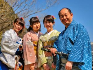 three women wearing kimonos standing nest to their father wearing traditional Japanese clothing, locate birth parents in Japan concept