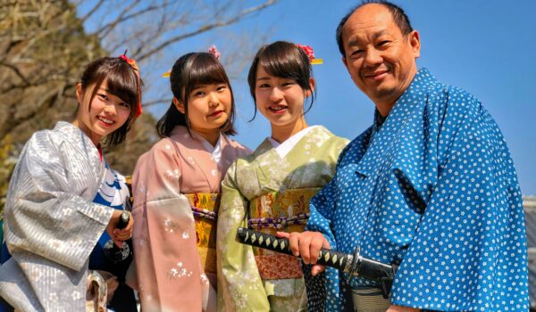 three women wearing kimonos standing nest to their father wearing traditional Japanese clothing, locate birth parents in Japan concept