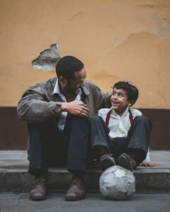 Belizean father and son sitting on the sidewalk; locate birth parents in Belize concept