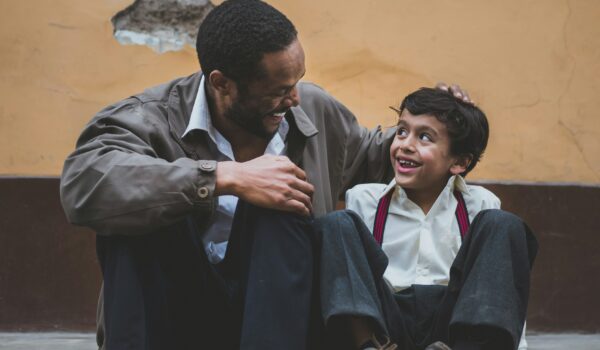 Belizean father and son sitting on the sidewalk; locate birth parents in Belize concept