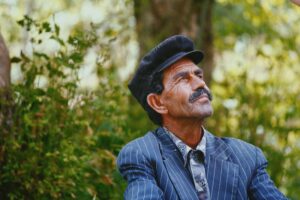 portrait shot of an Albanian father with plants in the background; locate birth parents in Albania concept