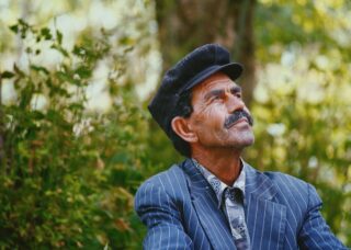 portrait shot of an Albanian father with plants in the background; locate birth parents in Albania concept