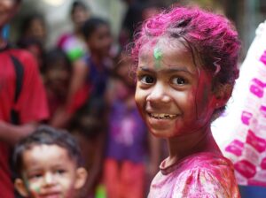 focused portrait of an Indian girl celebrating Holi festival; locate birth parents in India concept