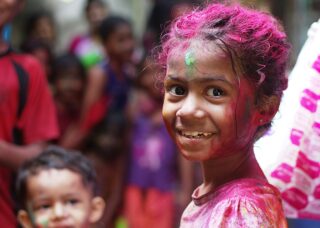 focused portrait of an Indian girl celebrating Holi festival; locate birth parents in India concept