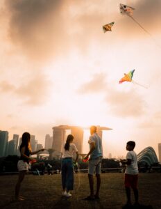 Singaporean family flying kites with the Marina Bay Sands in the background; locate birth parents in Singapore concept