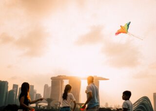 Singaporean family flying kites with the Marina Bay Sands in the background; locate birth parents in Singapore concept