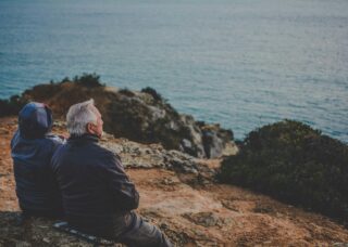 Portuguese grandparents sitting by the shore; locate birth parents in Portugal concept