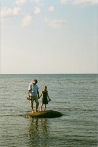 father and daughter standing on a small sand bar in the sea of Mērsraga pagasts, Latvia; locate birth parents in Latvia concept