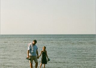 father and daughter standing on a small sand bar in the sea of Mērsraga pagasts, Latvia; locate birth parents in Latvia concept