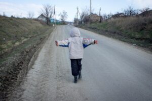 Moldovan kid running in a dirt road with his arms stretched; locate birth parents in Moldova concept