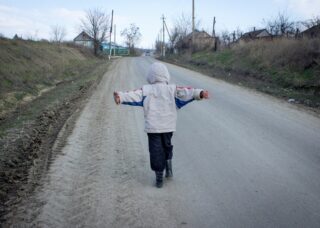 Moldovan kid running in a dirt road with his arms stretched; locate birth parents in Moldova concept