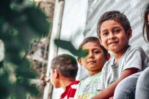 three boys from El Salvador, two looking at the camera and one looking at he back; locate birth parents in El Salvador concept