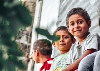 three boys from El Salvador, two looking at the camera and one looking at he back; locate birth parents in El Salvador concept