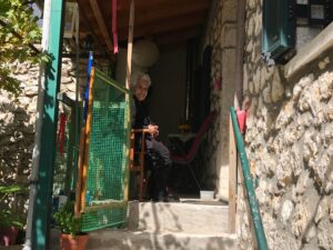 old Greek woman sitting on the porch of her house in Greece; locate birth parents in Greece concept