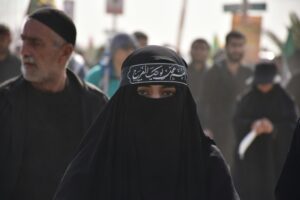 Arab Muslim woman wearing Niqab with other people in the background; locate birth parents in United Arab Emirates concept