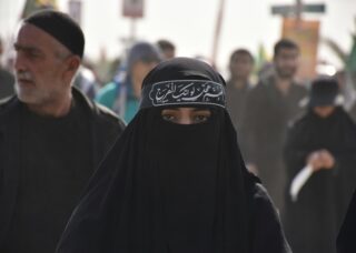 Arab Muslim woman wearing Niqab with other people in the background; locate birth parents in United Arab Emirates concept