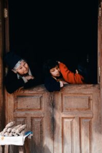 Bolivian grandmother and her two playing granddaughters inside their home; locate birth parents in Bolivia concept