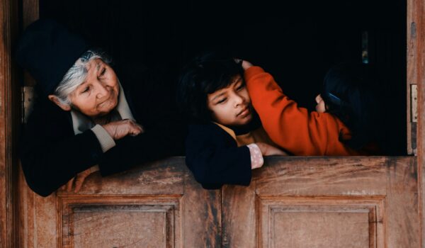 Bolivian grandmother and her two playing granddaughters inside their home; locate birth parents in Bolivia concept