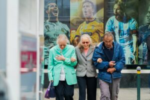 two old Swiss women with an old Swiss man walking with their hands together; locate birth parents in Switzerland concept