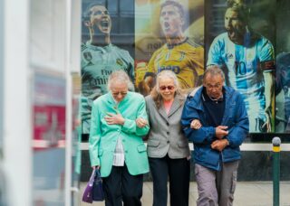 two old Swiss women with an old Swiss man walking with their hands together; locate birth parents in Switzerland concept