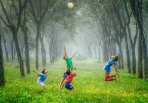 four Indonesian kids playing soccer in a field with trees; locate birth parents in Indonesia concept