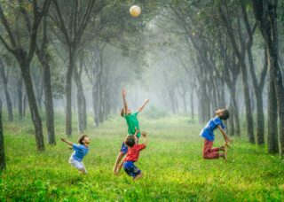 four Indonesian kids playing soccer in a field with trees; locate birth parents in Indonesia concept