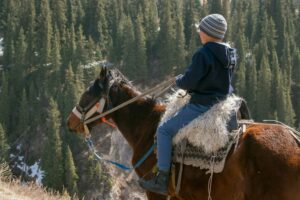 Kazakh boy riding a horse in Kolsai Lake, Kazakhstan; locate birth parents in Kazakhstan