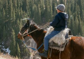 Kazakh boy riding a horse in Kolsai Lake, Kazakhstan; locate birth parents in Kazakhstan