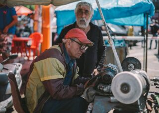 two Georgian grandfathers one looking at the camera and one sharpening a saw; locate birth parents in Georgia concept