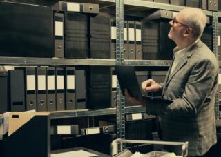 A man in a suit is focused on a laptop, appearing engaged in work or a discussion