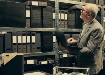 A man in a suit is focused on a laptop, appearing engaged in work or a discussion